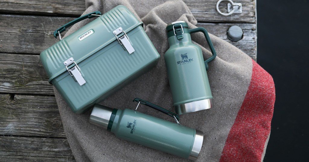 Two green thermos containers and lunch box on a wood outdoor background.