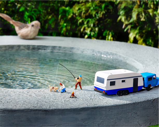 miniature figurines camping and fishing atop a bird bath