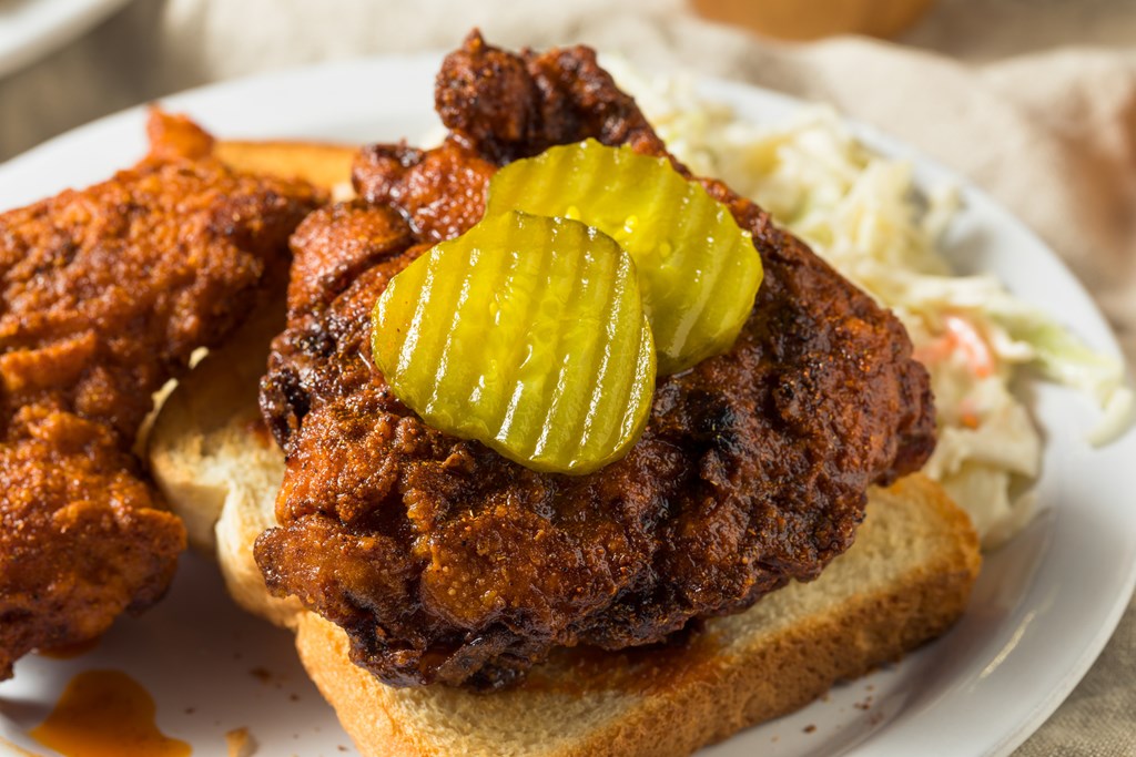 Homemade Nashville hot chicken served over white bread with pickle slices.
