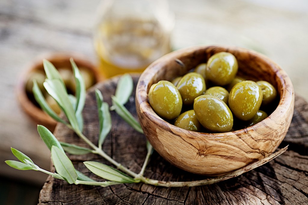 Fresh olives and olive oil branch rustic wooden background. 