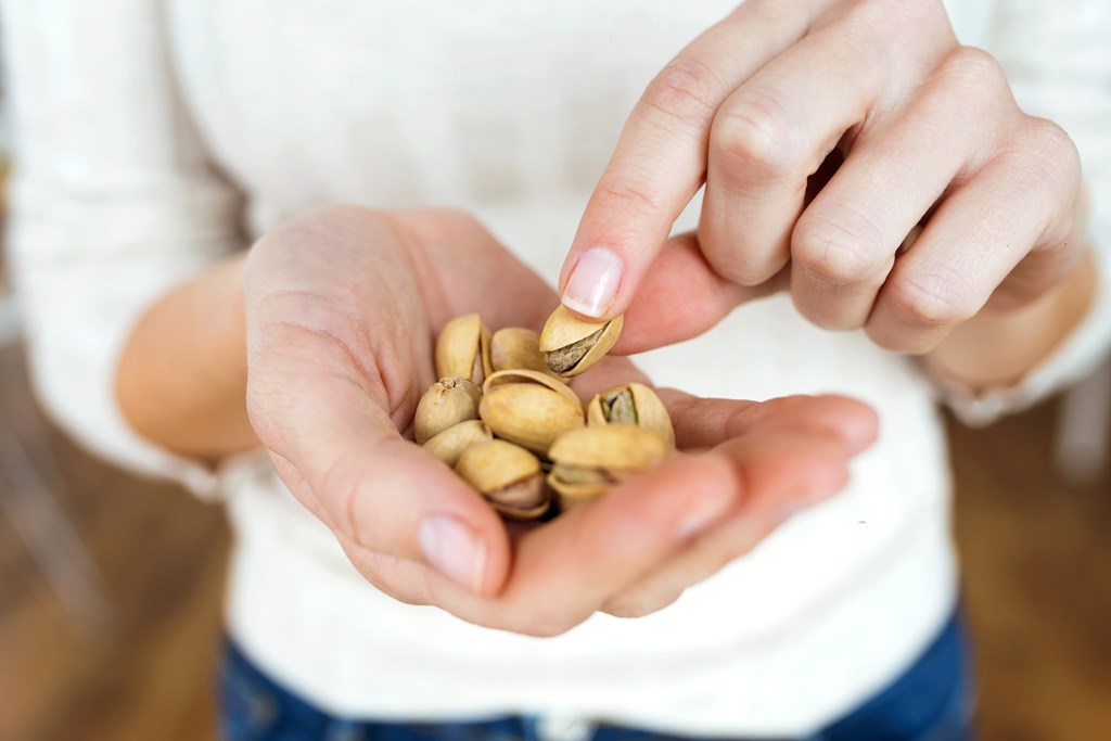 Young woman hands holding and picking up a pistachios nuts.