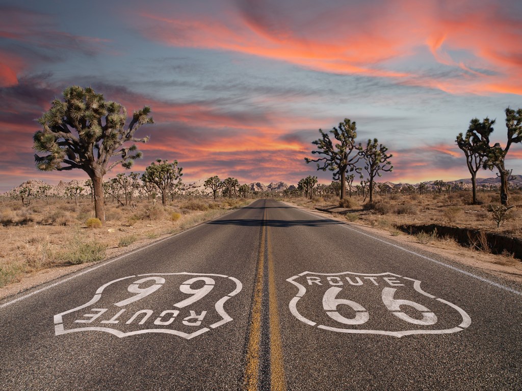 Route 66 with Joshua Trees and sunset sky in California's Mojave Desert.