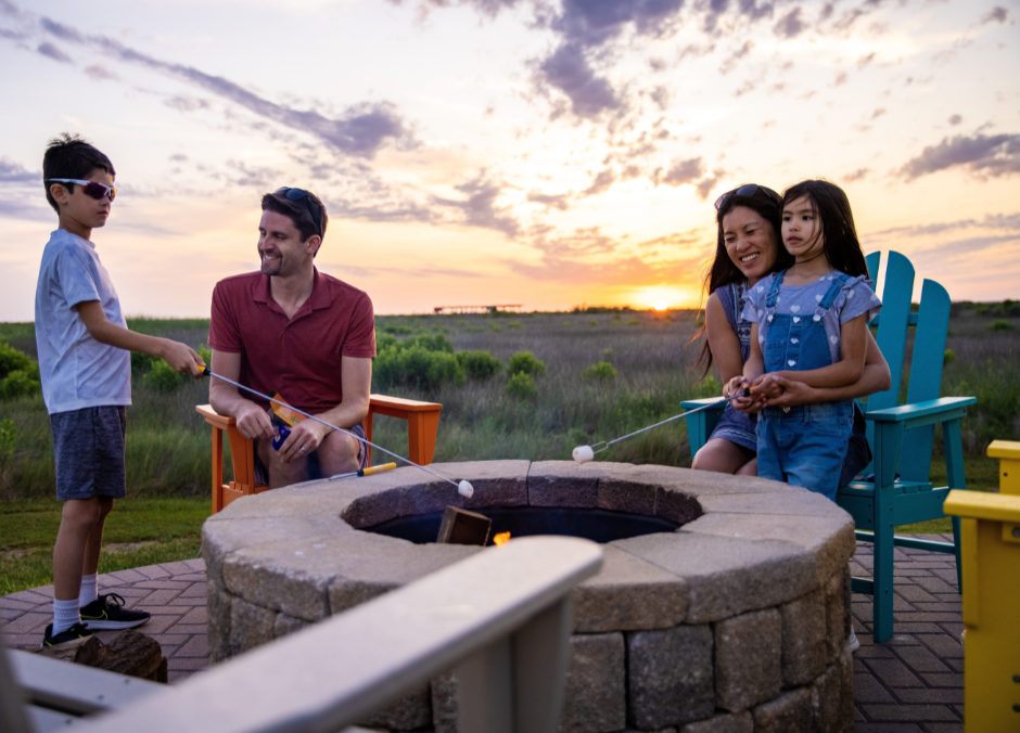 Family toasts marshmallows around a campfire at sunset at Galveston Island KOA