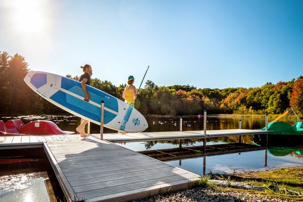 Man preparing to paddleboard at Strafford/Lake Winnipesaukee S. KOA Holiday, New Hampshire