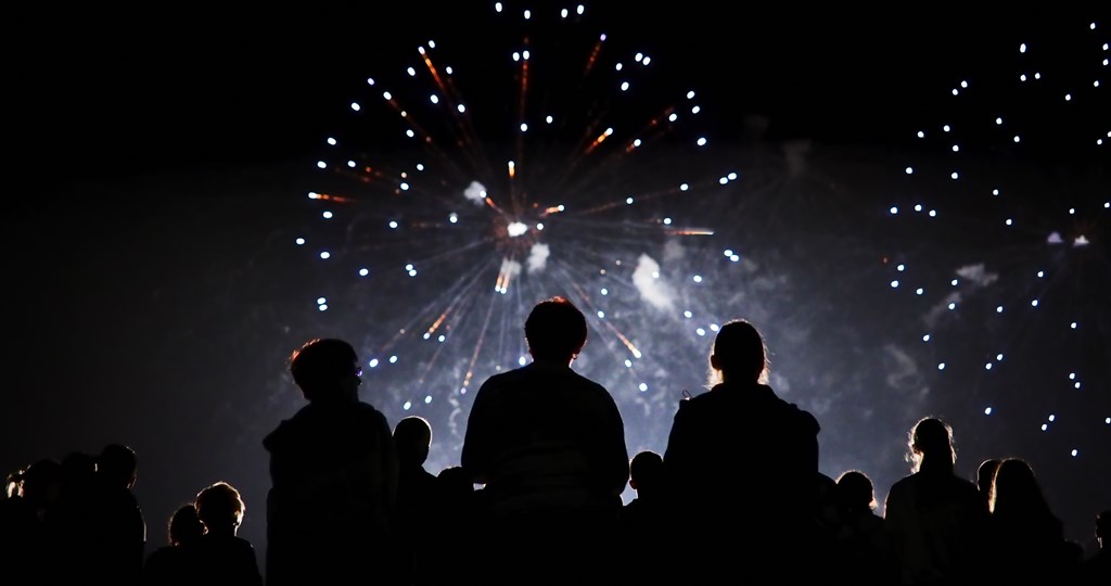 Silhouette of a crowd watching fireworks at night