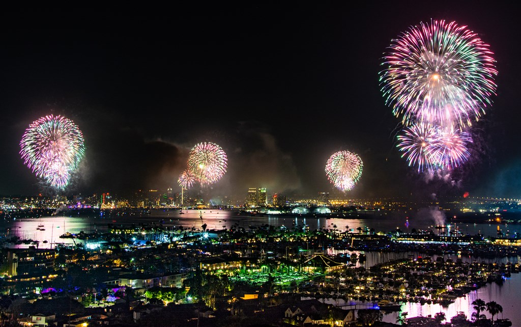 Multi-colored fireworks over San Diego Bay at night on Fourth of July with skyline in background