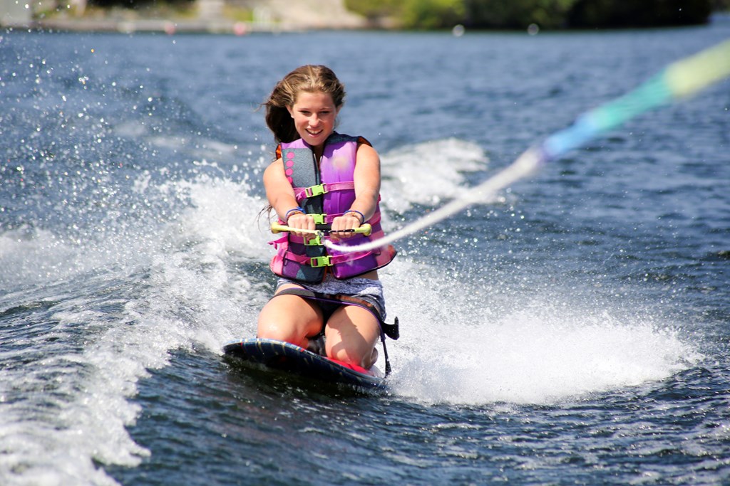 A teenage girl enjoying her first try on a kneeboard. She is on a lake in Muskoka, Ontario, Ontario, Canada