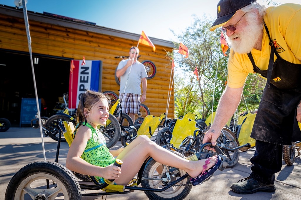 Man helping a little girl ride a bicycle.