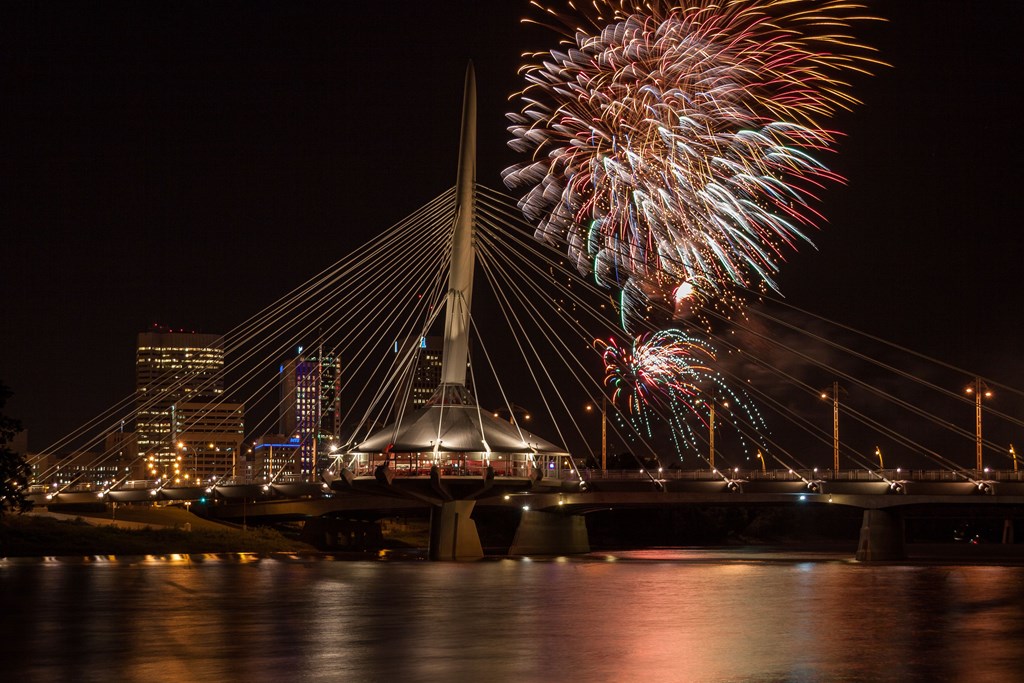 Nighttime view of Provencher bridge in Winnipeg with fireworks in the sky in the sky