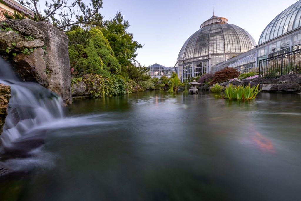 The waterfall and lake in long exposure with Anna Scripps Whitcomb Conservatory in the background.