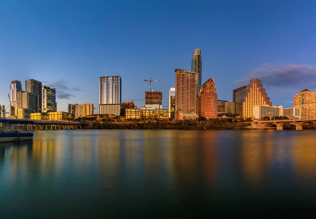 Panorama with downtown high-rises reflecting sunset golden hour light viewed across Lady Bird Lake or Town Lake on Colorado River in Austin, Texas USA