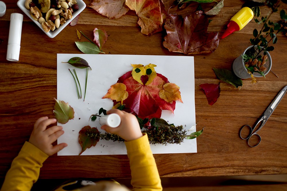 Toddler crafting with autumn leaves.