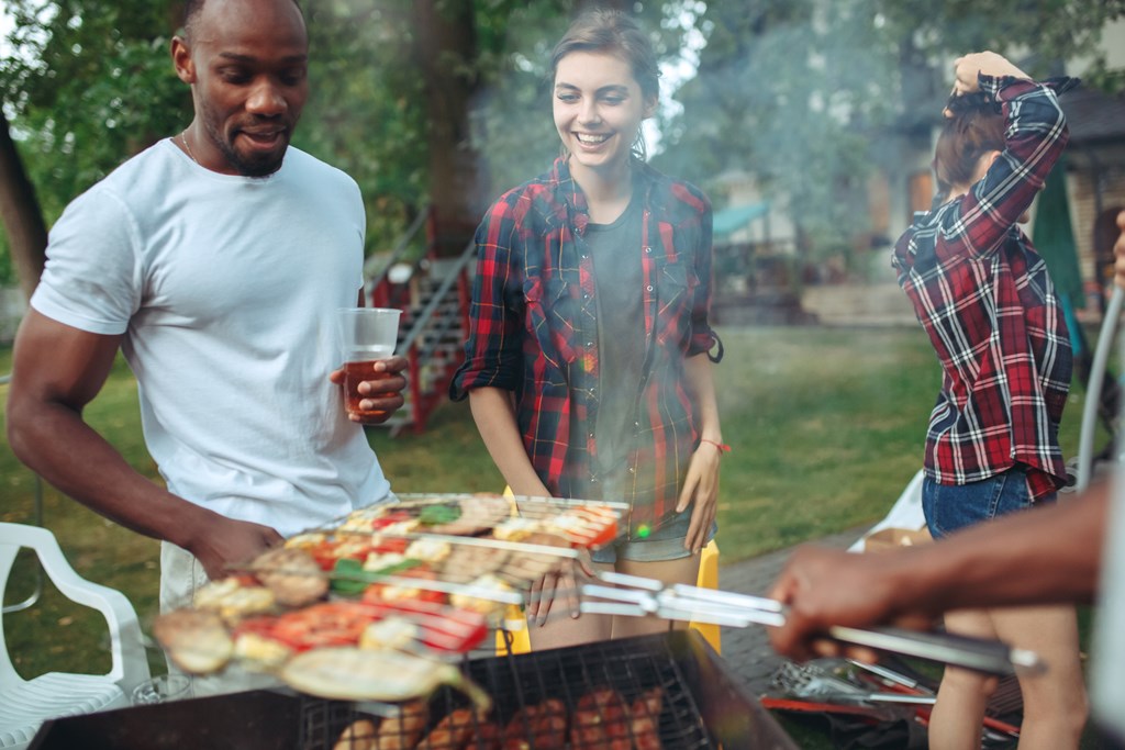 `Group of friends making grilling over a barbecue at the campground.
