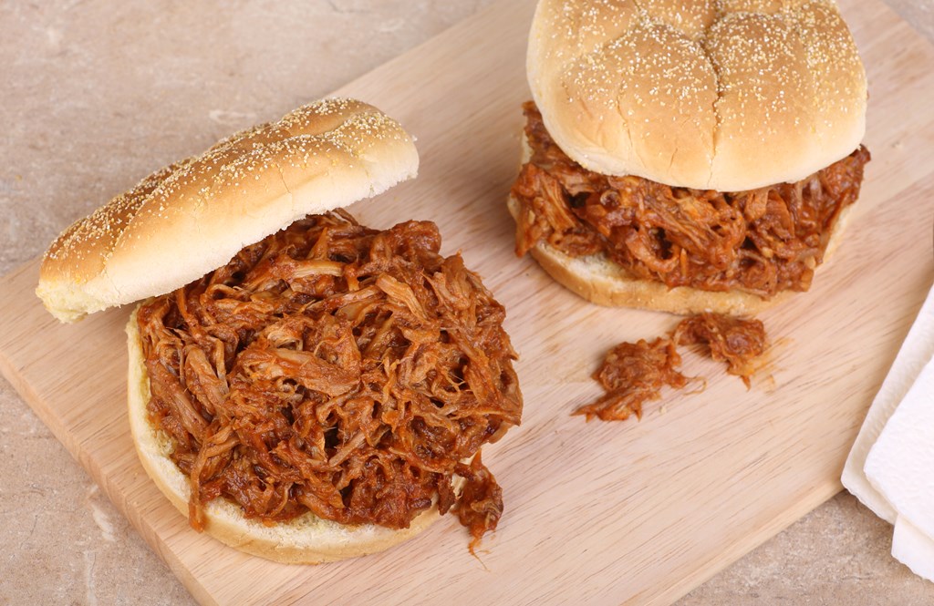 Two pulled pork sandwiches on a cutting board