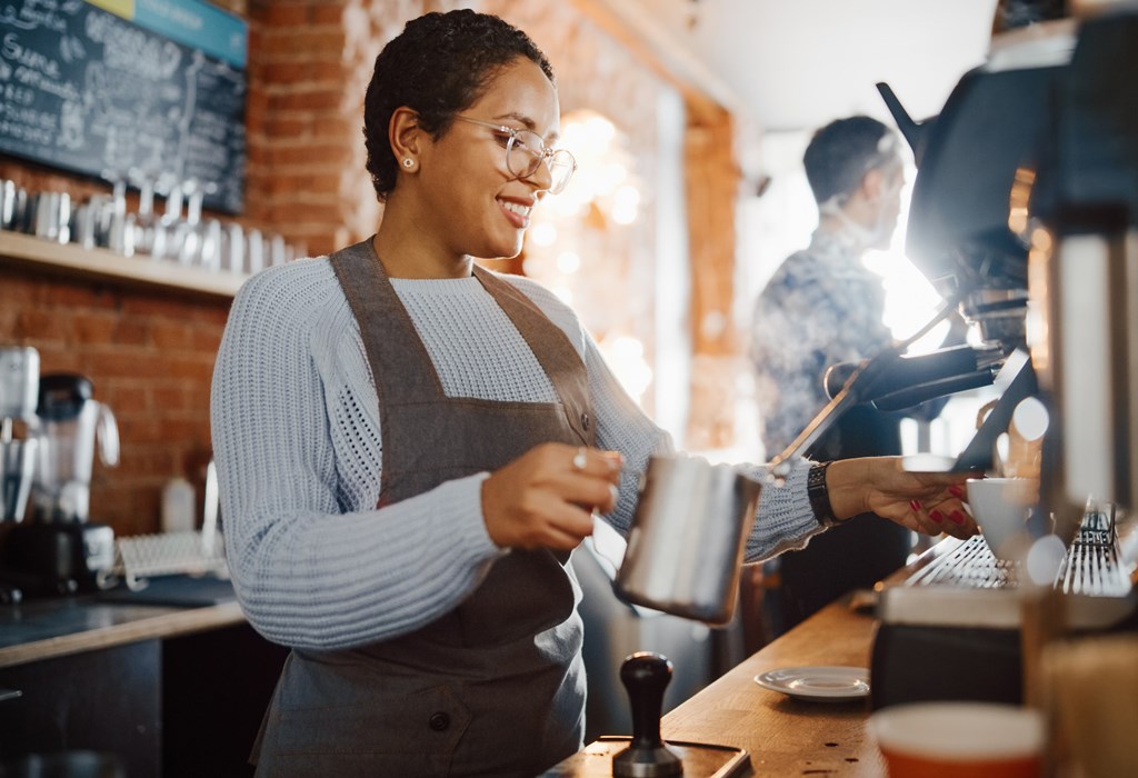 Female barista makes espresso during a sunny morning in a coffee shop.