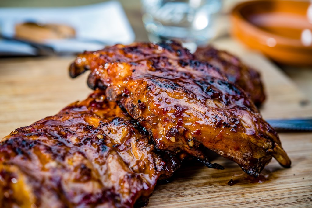 Close up of golden colored juicy roasted spare ribs on a wooden cutting board.