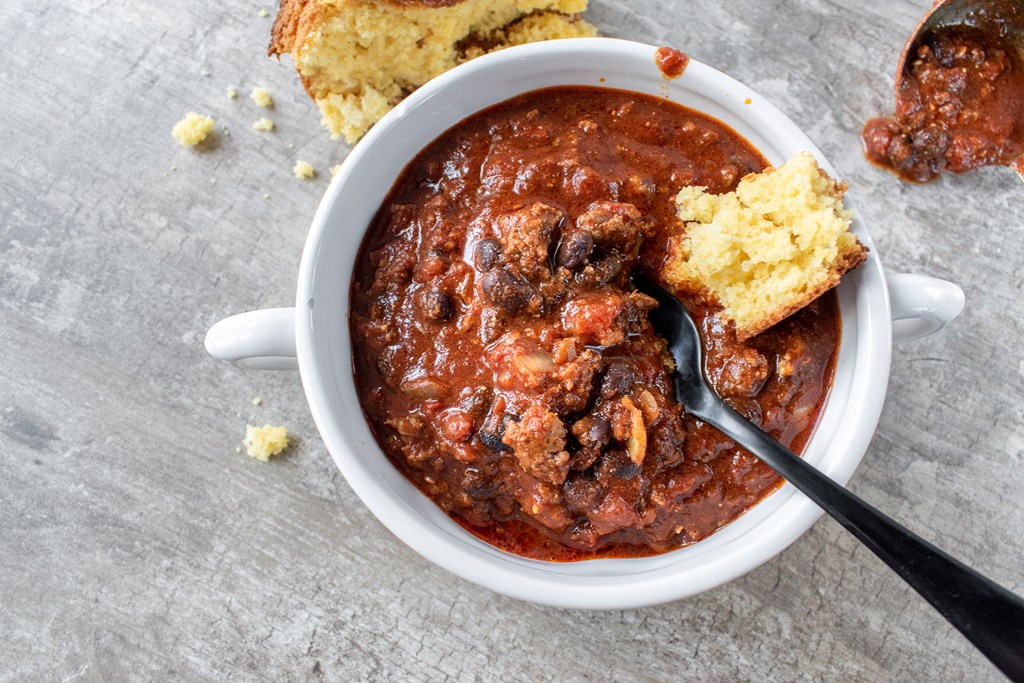 `bowl of chili with black beans and cornbread flat lay