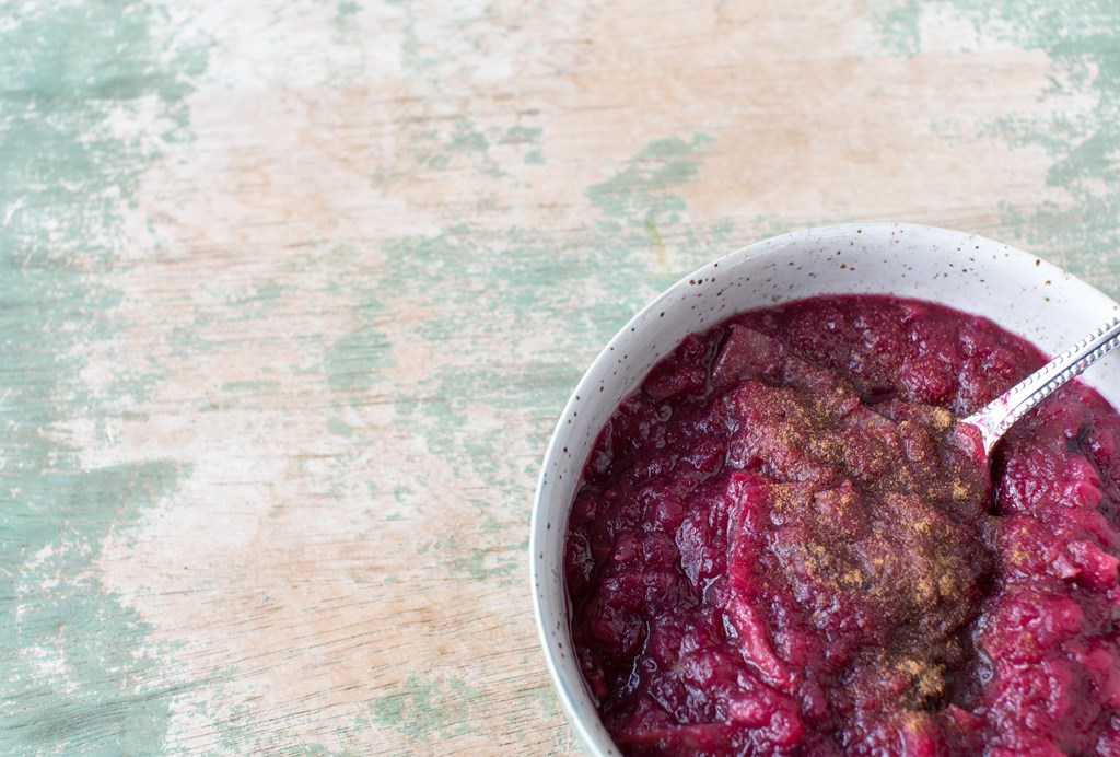 Homemade fresh stewed apples with blueberries and cinnamon topping. Served isolated on weathered and wooden background.