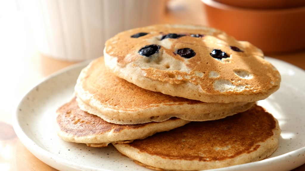 Large American pancakes with blueberries on plate with natural morning light.