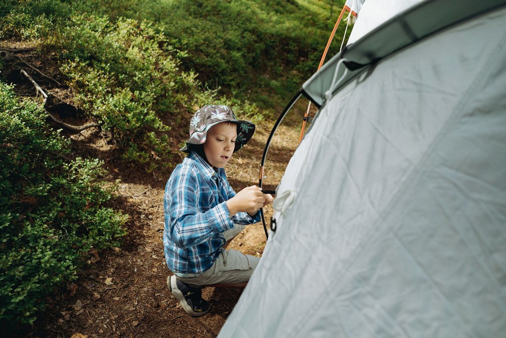 A young boy helps pitch a tent on a KOA camping trip.