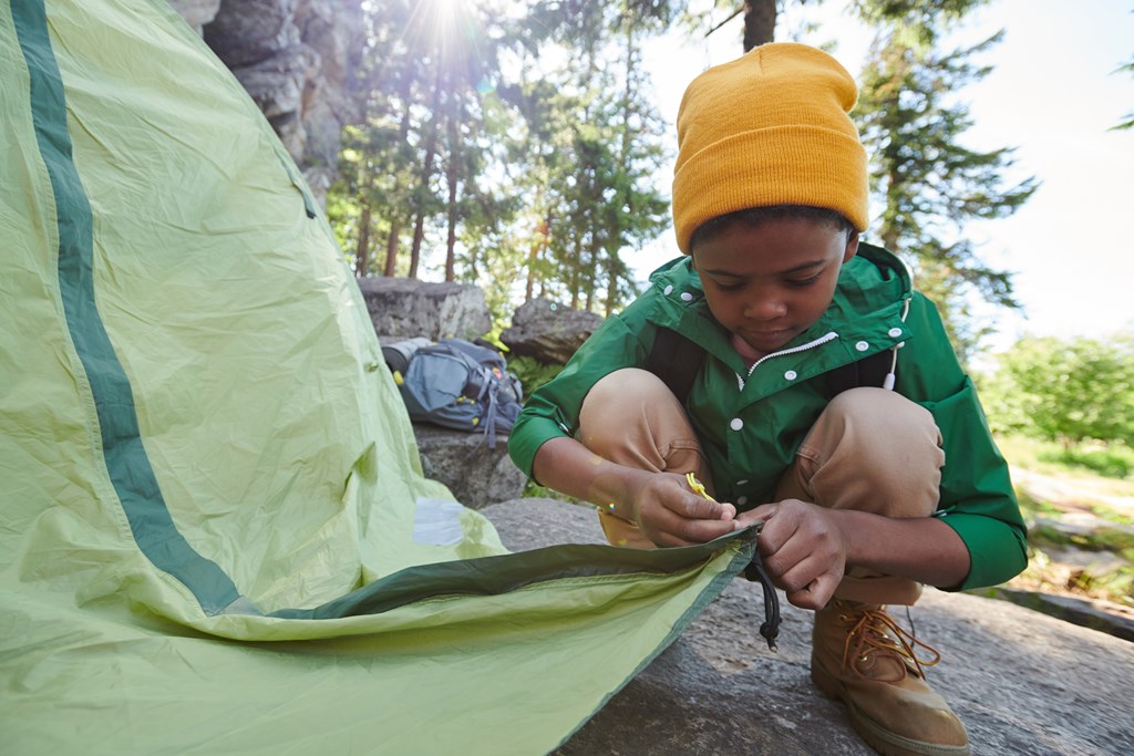 Little boy setting up the tent. 