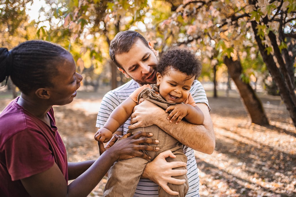Boy in the arms of his parents on a fall day.