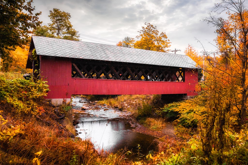 Beautiful Vermont covered bridge surrounded by colorful fall foliage.