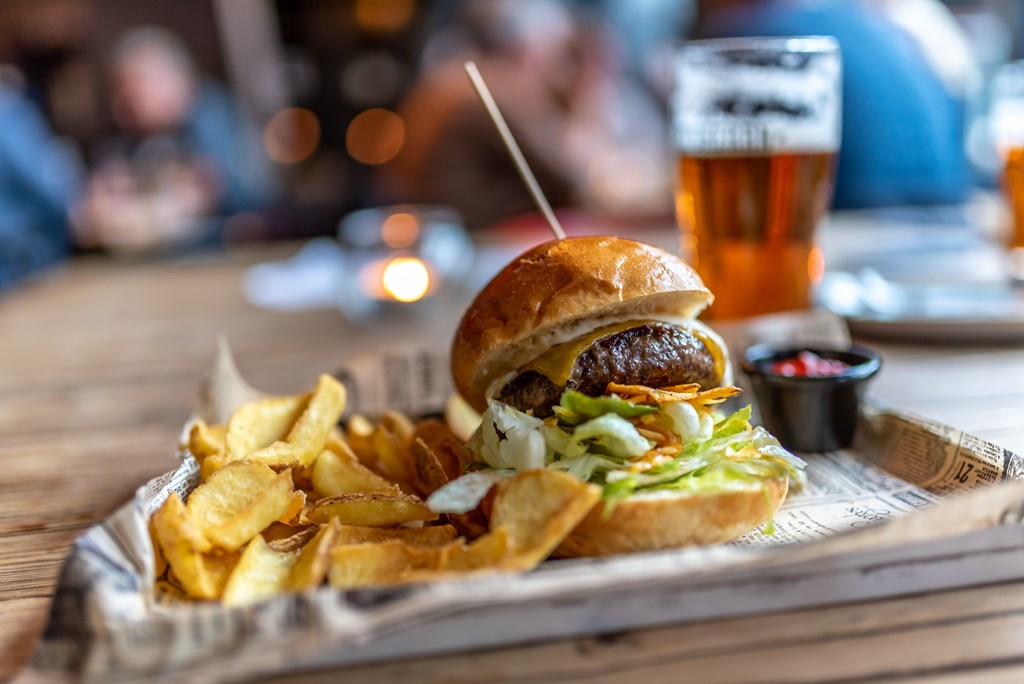 A gourmet burger and fries on a metal tray. A beer sits in the background.
