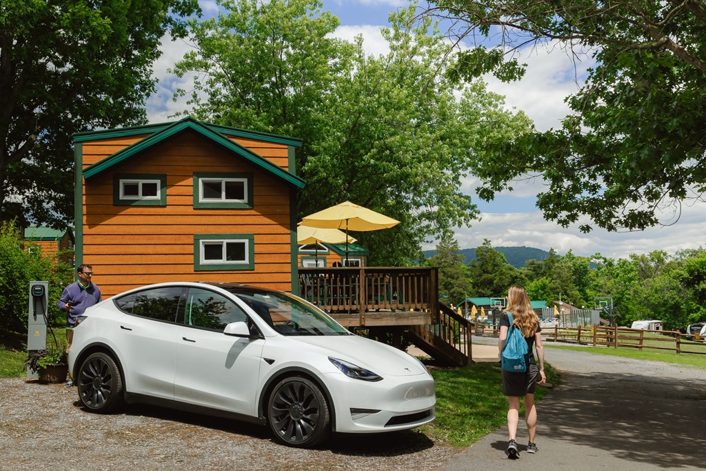 Couple at a KOA campground Deluxe Cabin with a Tesla electric vehicle.