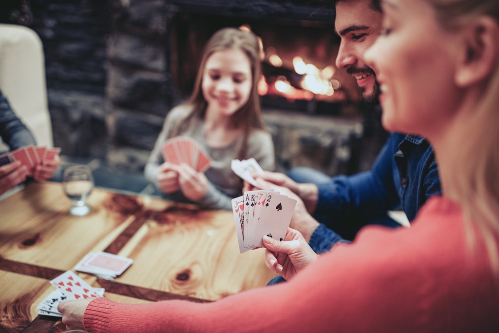 Young family playing card game in a cabin by the fire.