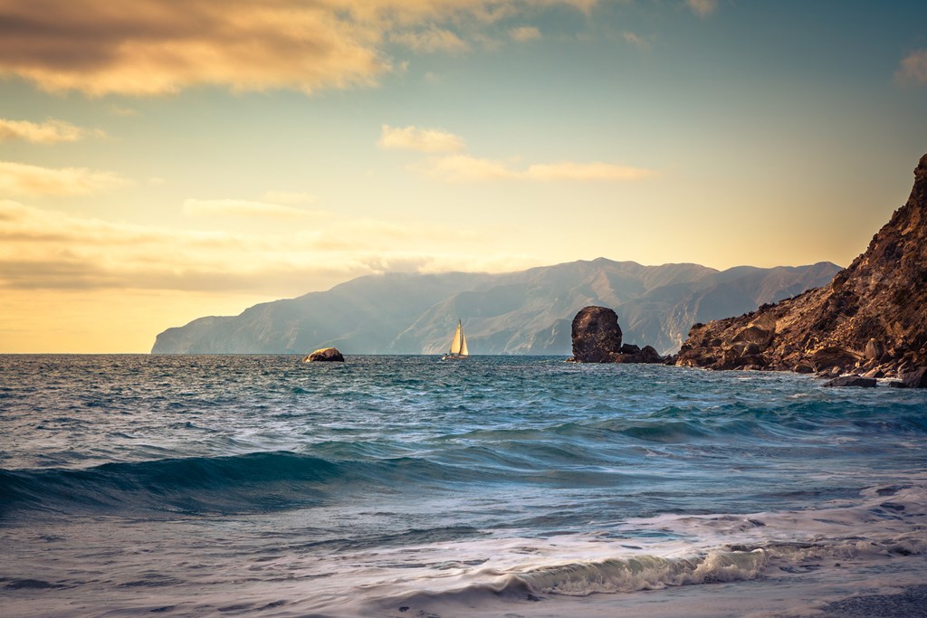 Sentinel Rock as seen from Ben Weston Beach, Catalina Island, California. A sailboat drifts toward Little Harbor in the background.