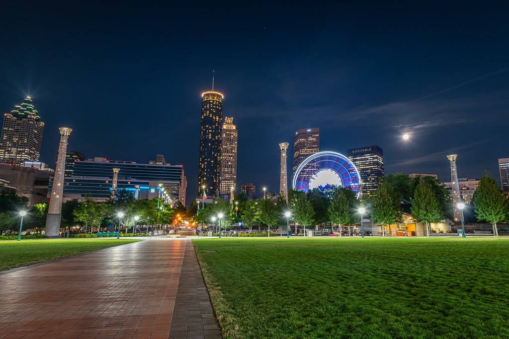 A night time view of Centennial Olympic Park in Atlanta with the city skyline and ferris wheel in the background.