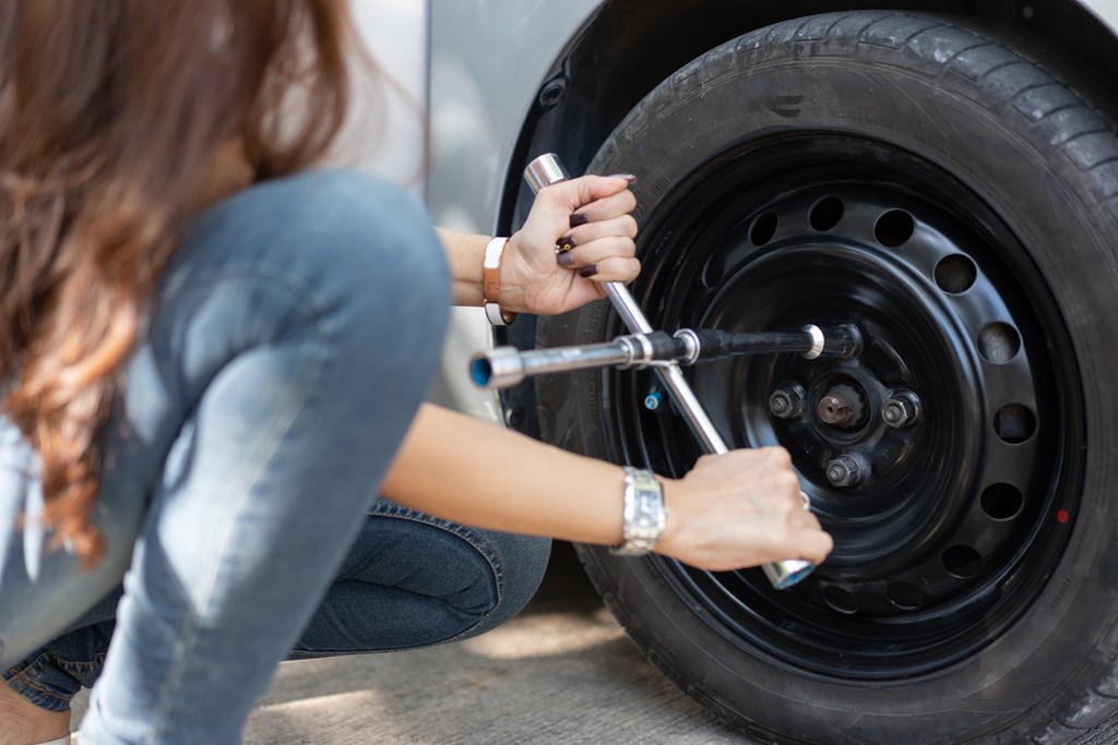 Closeup of woman changing a flat tire.