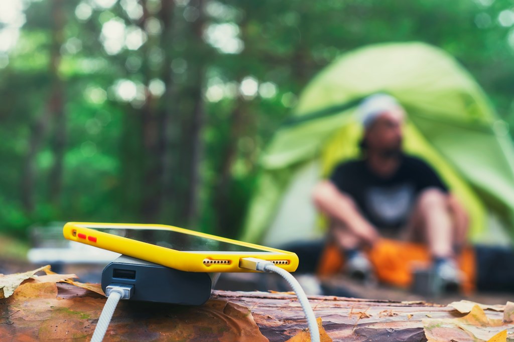 A smartphone charging in the foreground of a tent on a KOA campsite.
