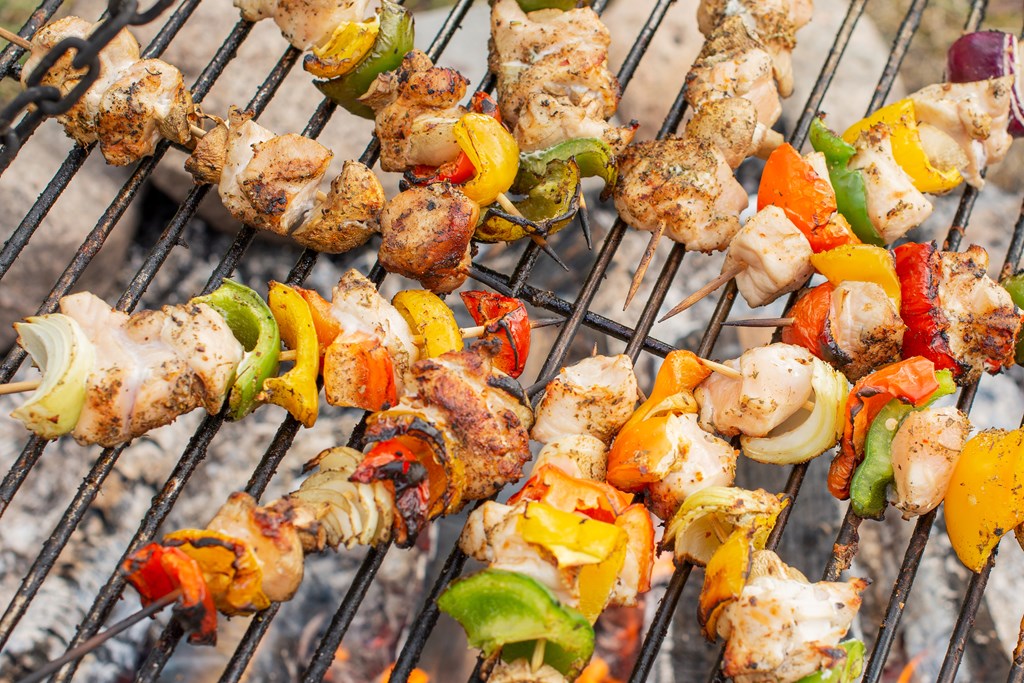 Chicken kababs with veggies on BBQ grilling grate closeup.