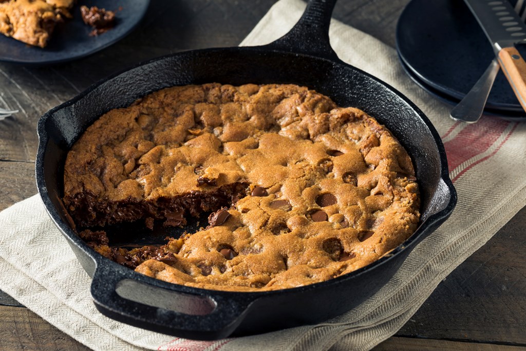A large chocolate chip cookie in a cast iron skillet.