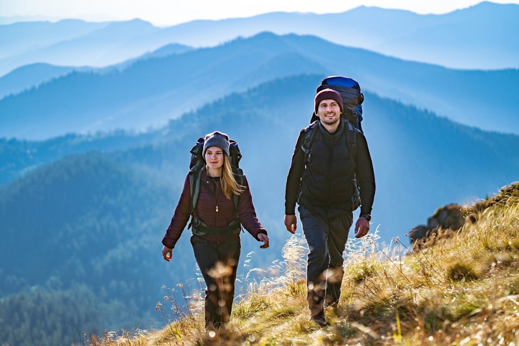 Young couple hike a mountain trail on a backpacking trip.