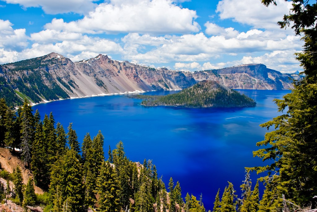 Crater Lake from a scenic overlook on a summer day with fluffy clouds.