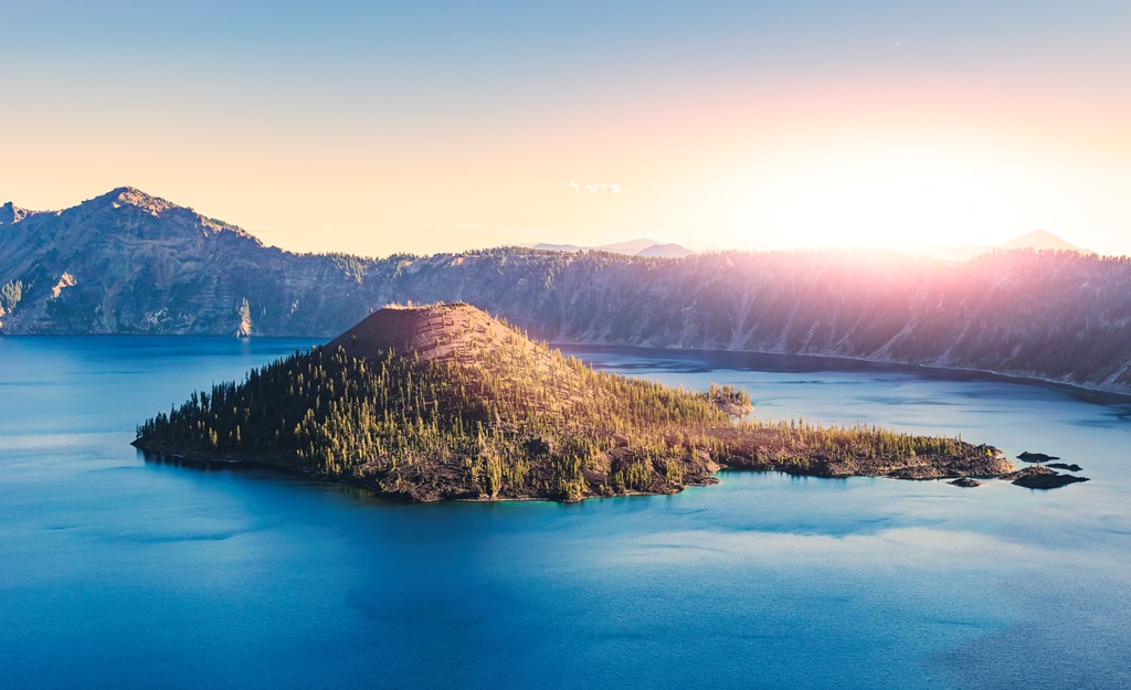 Scenic view of Crater Lake National Park in Oregon with the sun rising over the mountains.