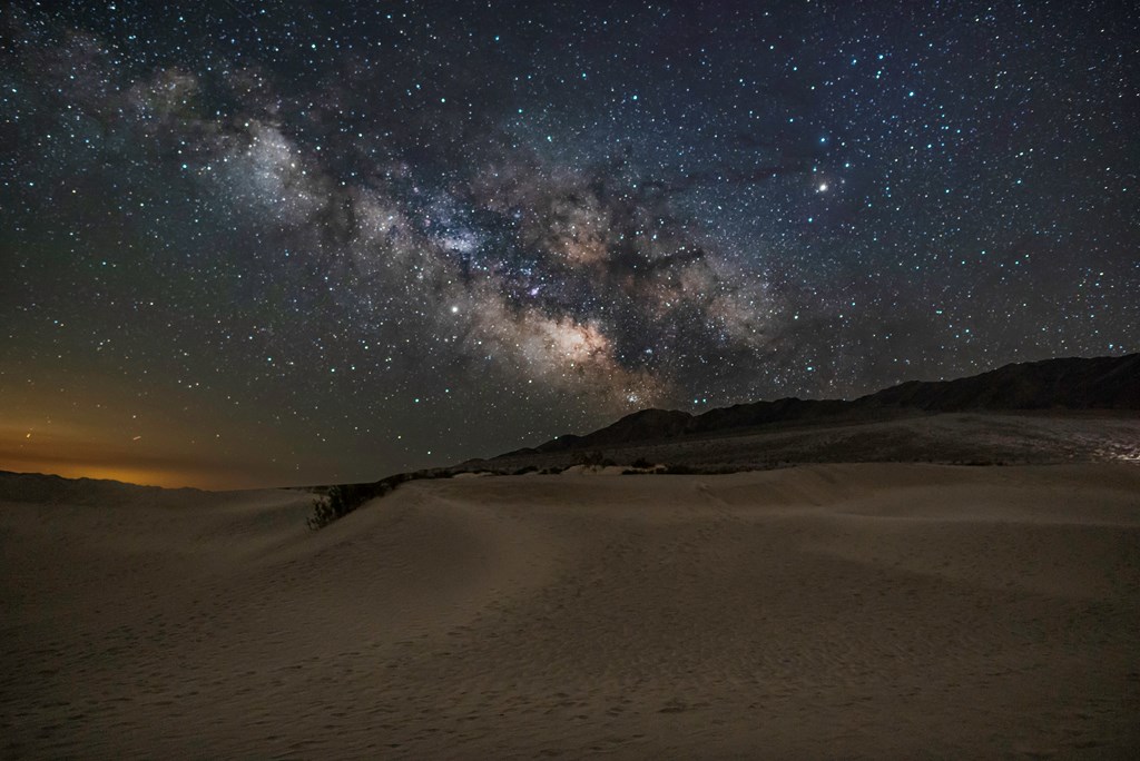 The Milky Way shines over the desert landscape of Death Valley National Park.