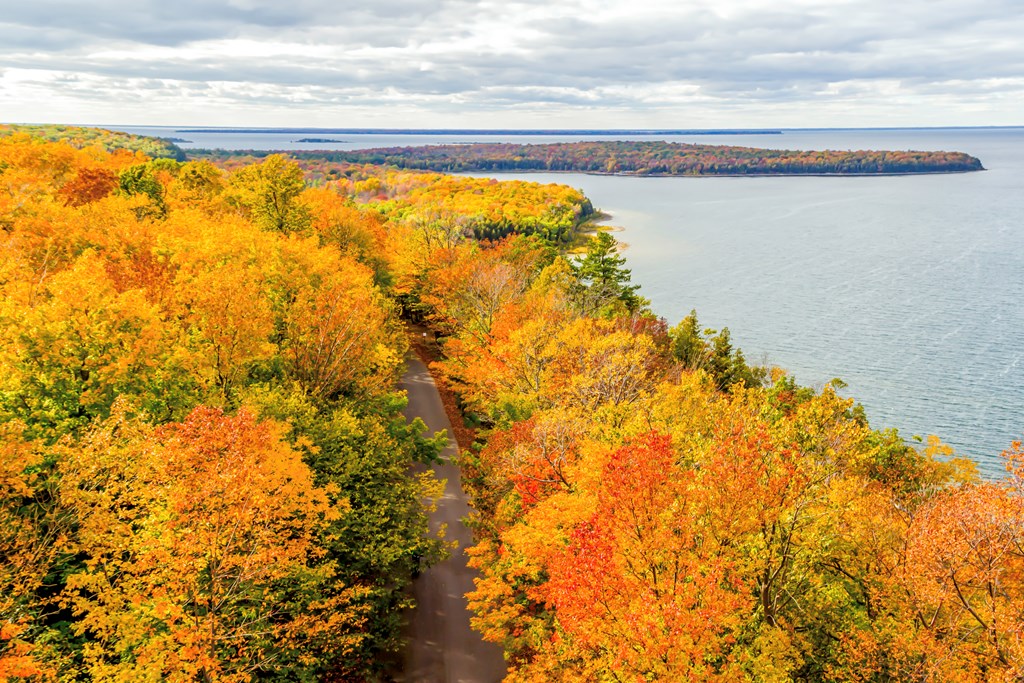 Aerial view of peaceful road near a lake with fall colors in Door County, Wisconsin.