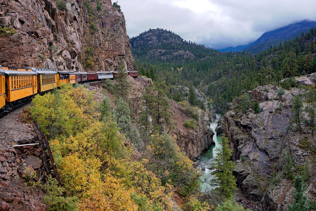 Durango and Silverton Narrow Gauge Railroad traveling along the side of mountain and above the Animas river.