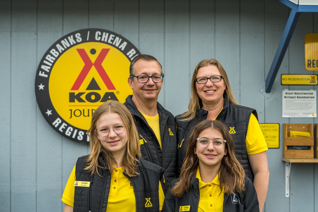 A family dressed in yellow shirts ands black vests in front a campground store.
