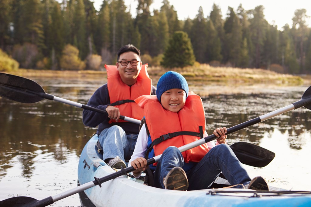 Father and son kayaking on a rural lake.