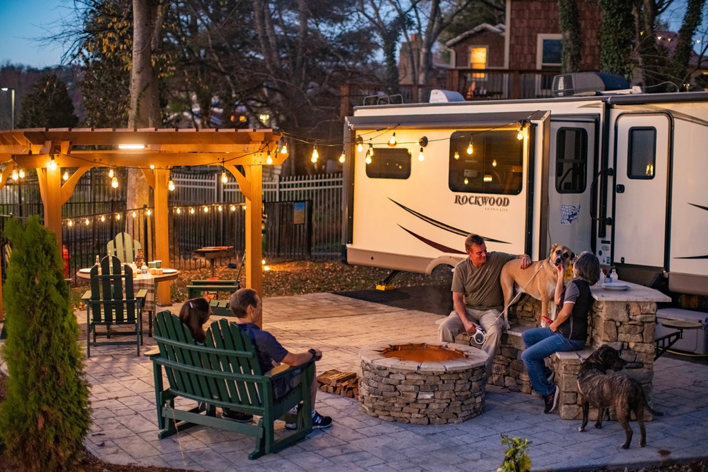 A family sits on a patio in front of their RV.