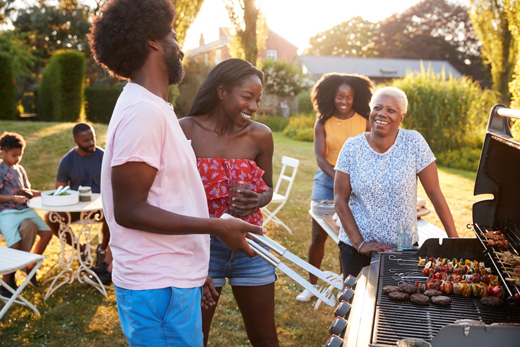 A multi-generational family gathers around the grill.