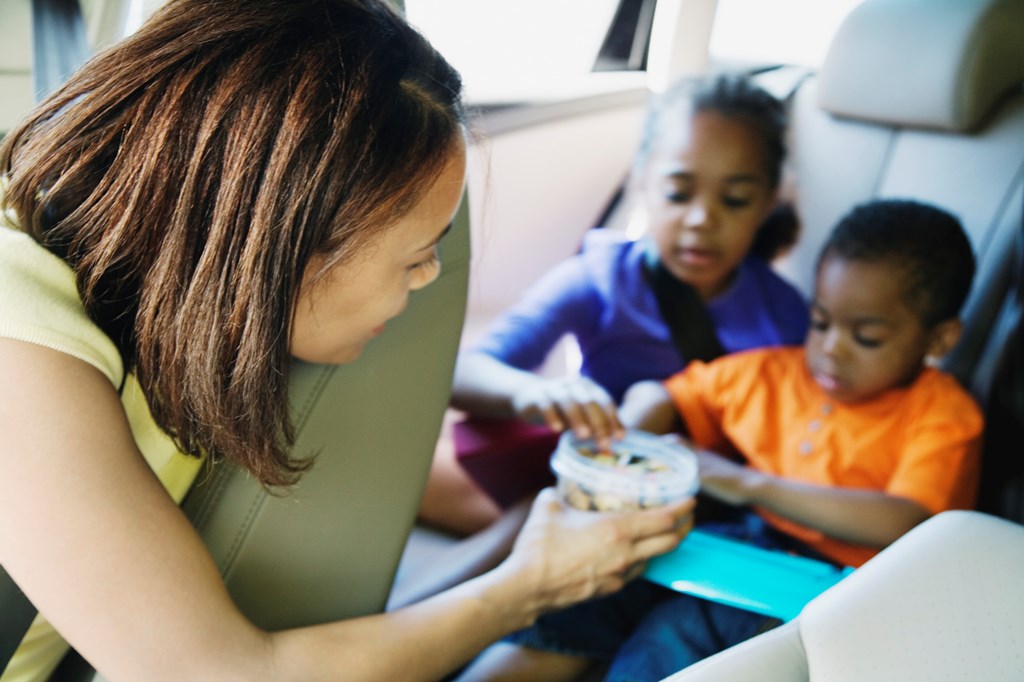 Mom giving her kids a snack in the car.