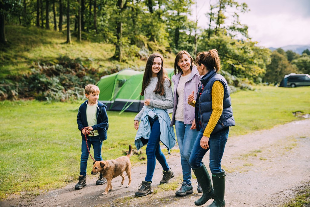 A happy family takes a dog on a walk at the campground.