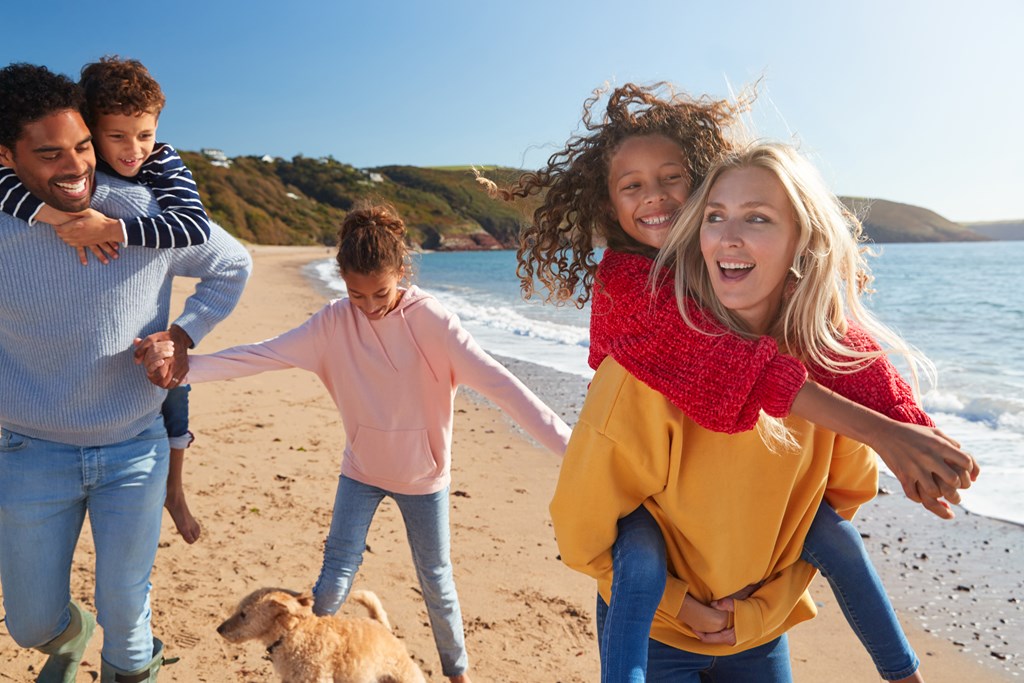 Parents giving their kids piggy back rides as the stroll along the beach.