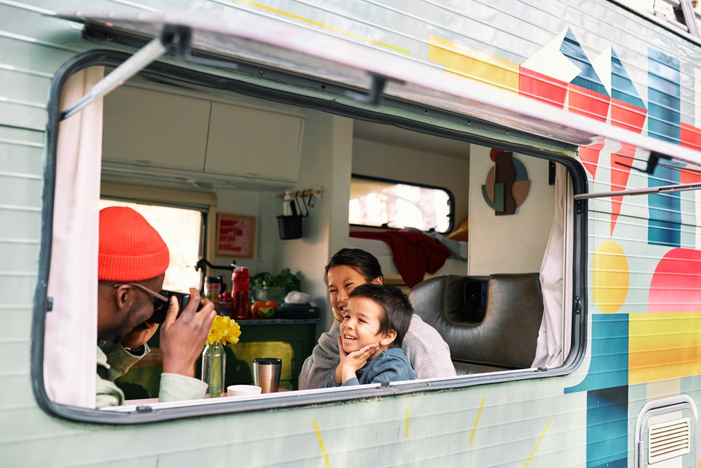 A father takes a photo of his wife and son inside their RV.